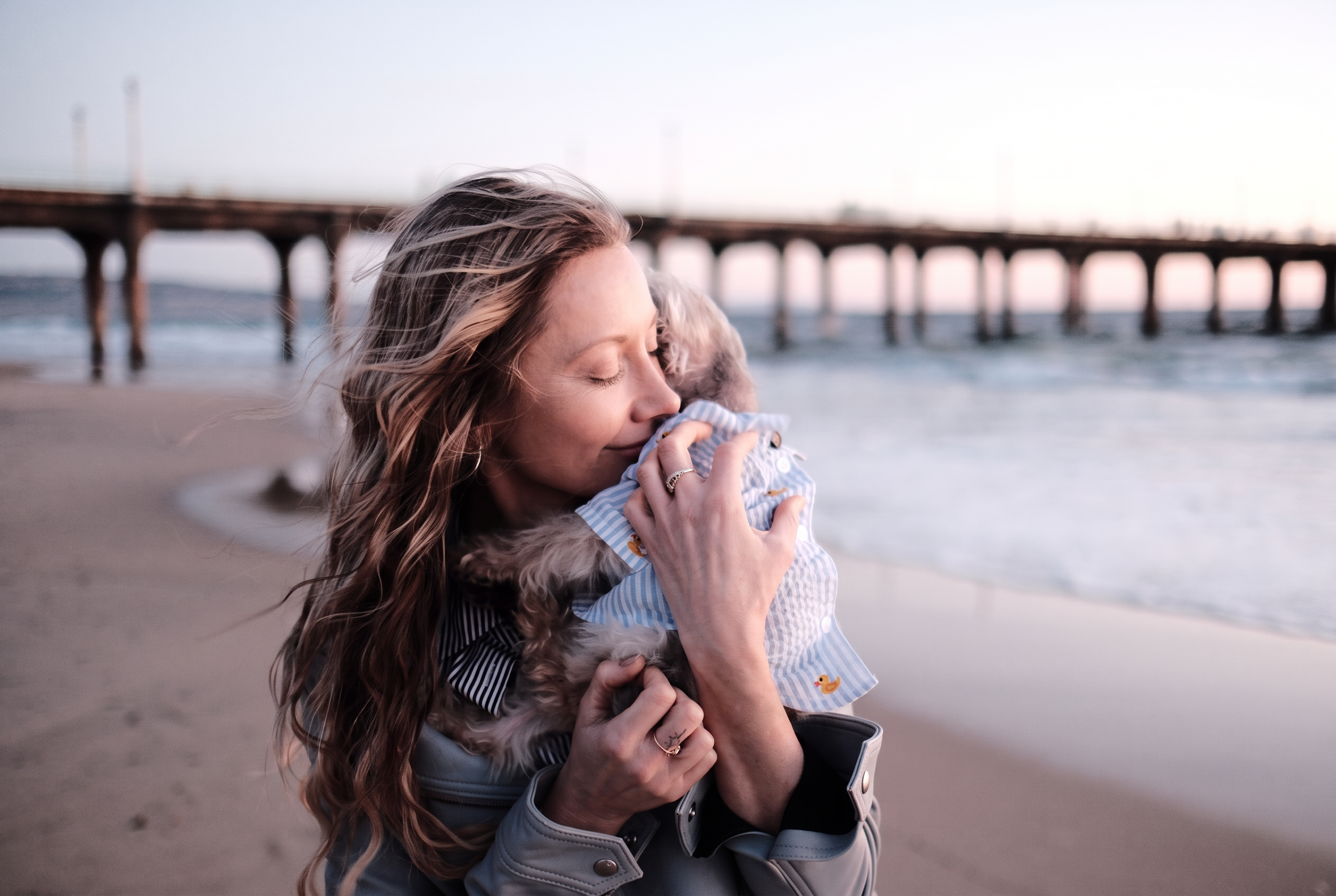 Tatyana holding her dog on the beach by the pier